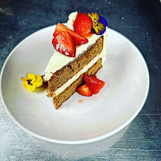 Close up a slice of cake with a strawberry and flower topping