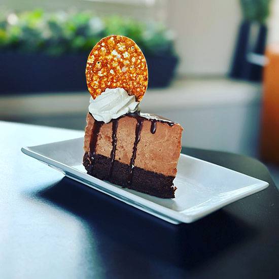 Slice of double chocolate cake with whipped cream and a wafer