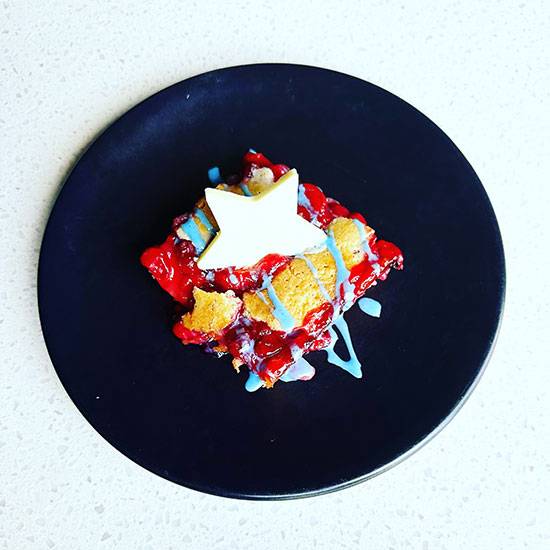 Close up a red, white, and blue desert served on a black plate