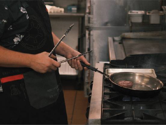 Seasoning co-owner cooking steak on the stove