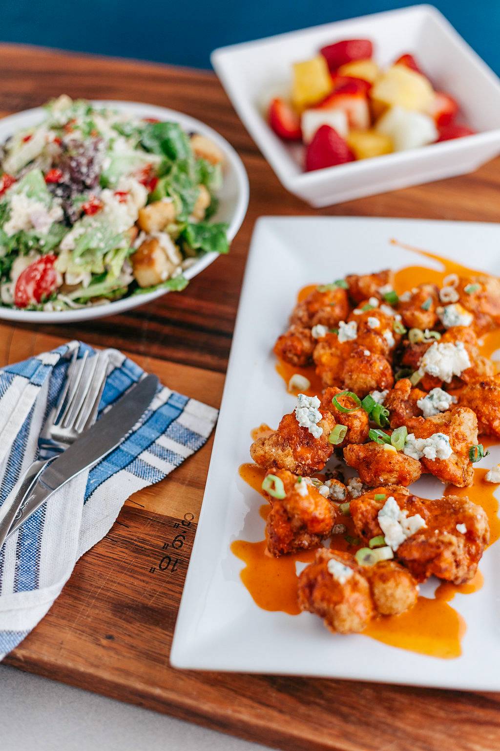 Buffalo cauliflower and salad served on a wooden tray